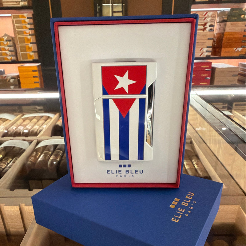 A framed Cuban flag lighter by Elie Bleu Paris, displayed on top of a blue Elie Bleu box inside a cigar shop.