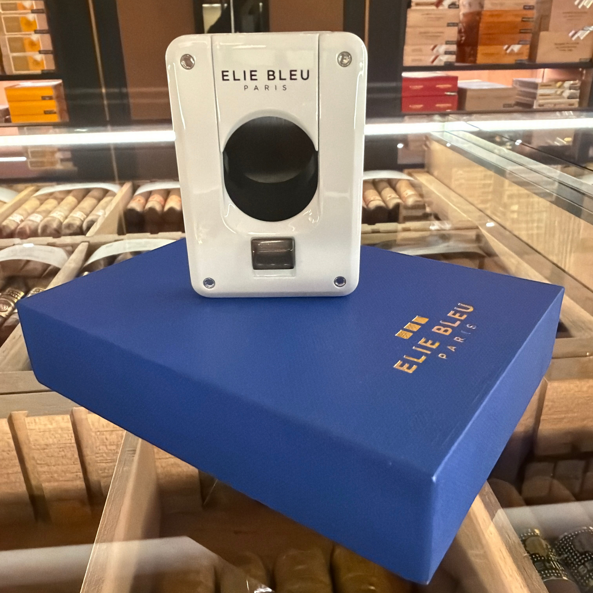 HAMILTON ELIE BLEU C-4 cigar cutter in white with black ion plated blade, displayed on a blue branded gift box.