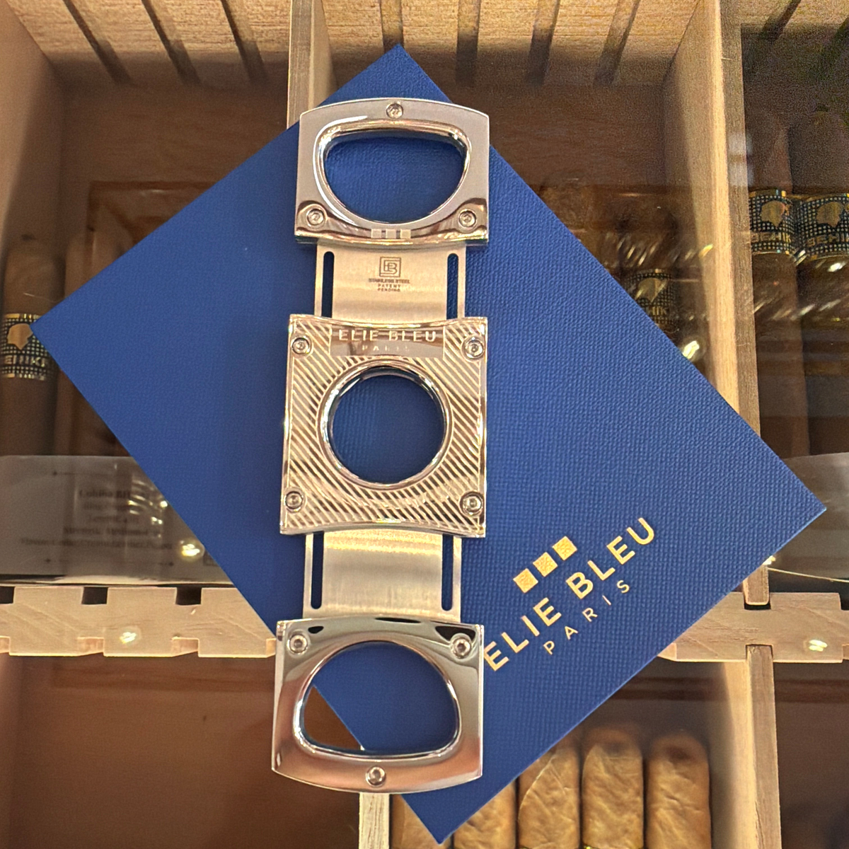 HAMILTON ELIE BLEU cigar cutter in polished stainless steel with diagonal line engraving on a blue branded display box