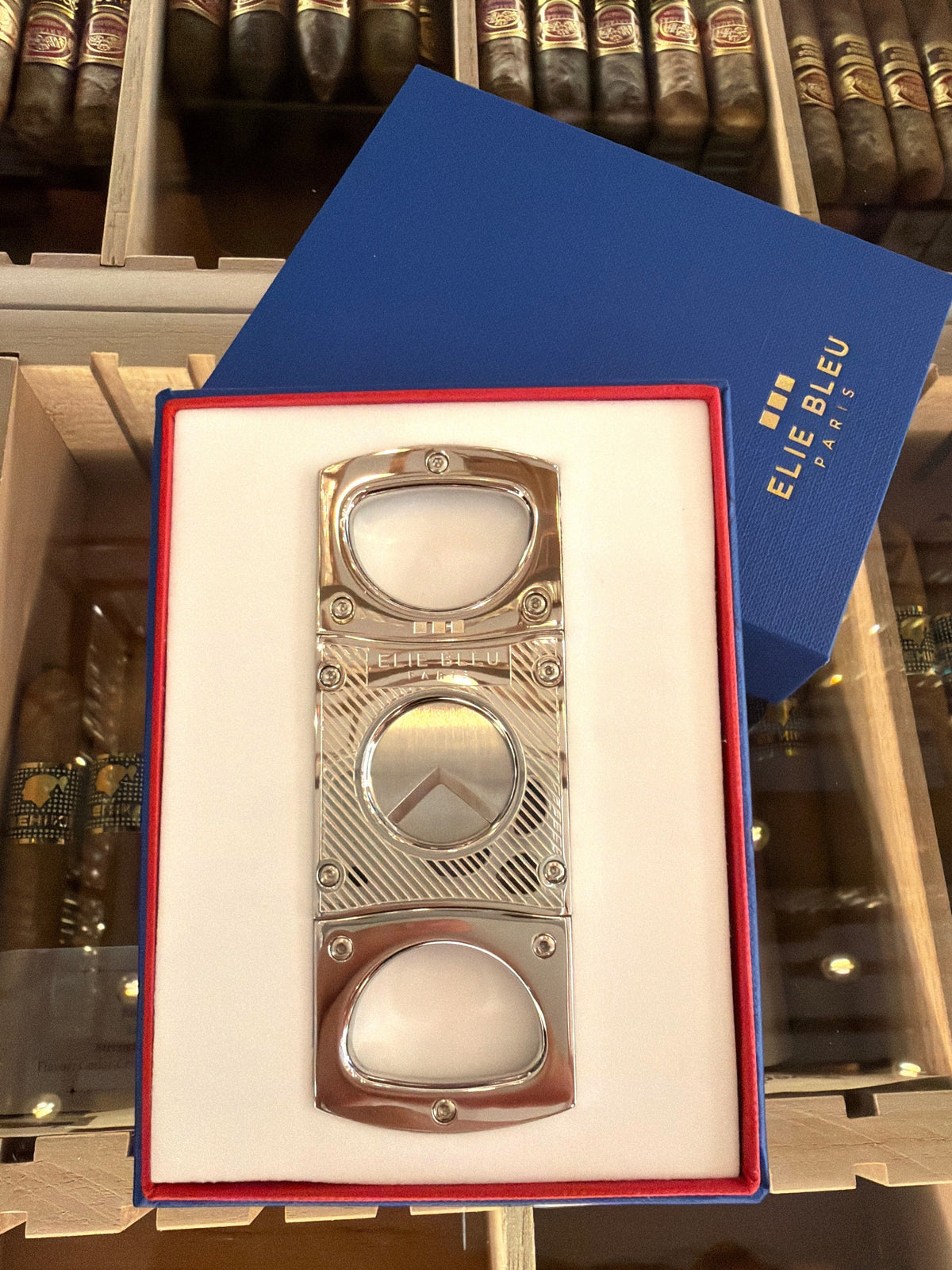 HAMILTON ELIE BLEU cigar cutter in polished stainless steel with diagonal line engraving in a blue presentation box.