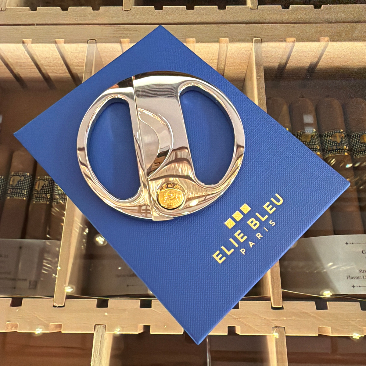 HAMILTON ELIE BLEU round cigar cutter featuring polished silver handles and a gold button on a blue display box