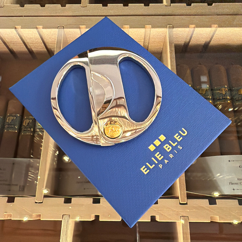 HAMILTON ELIE BLEU round cigar cutter featuring polished silver handles and a gold button on a blue display box